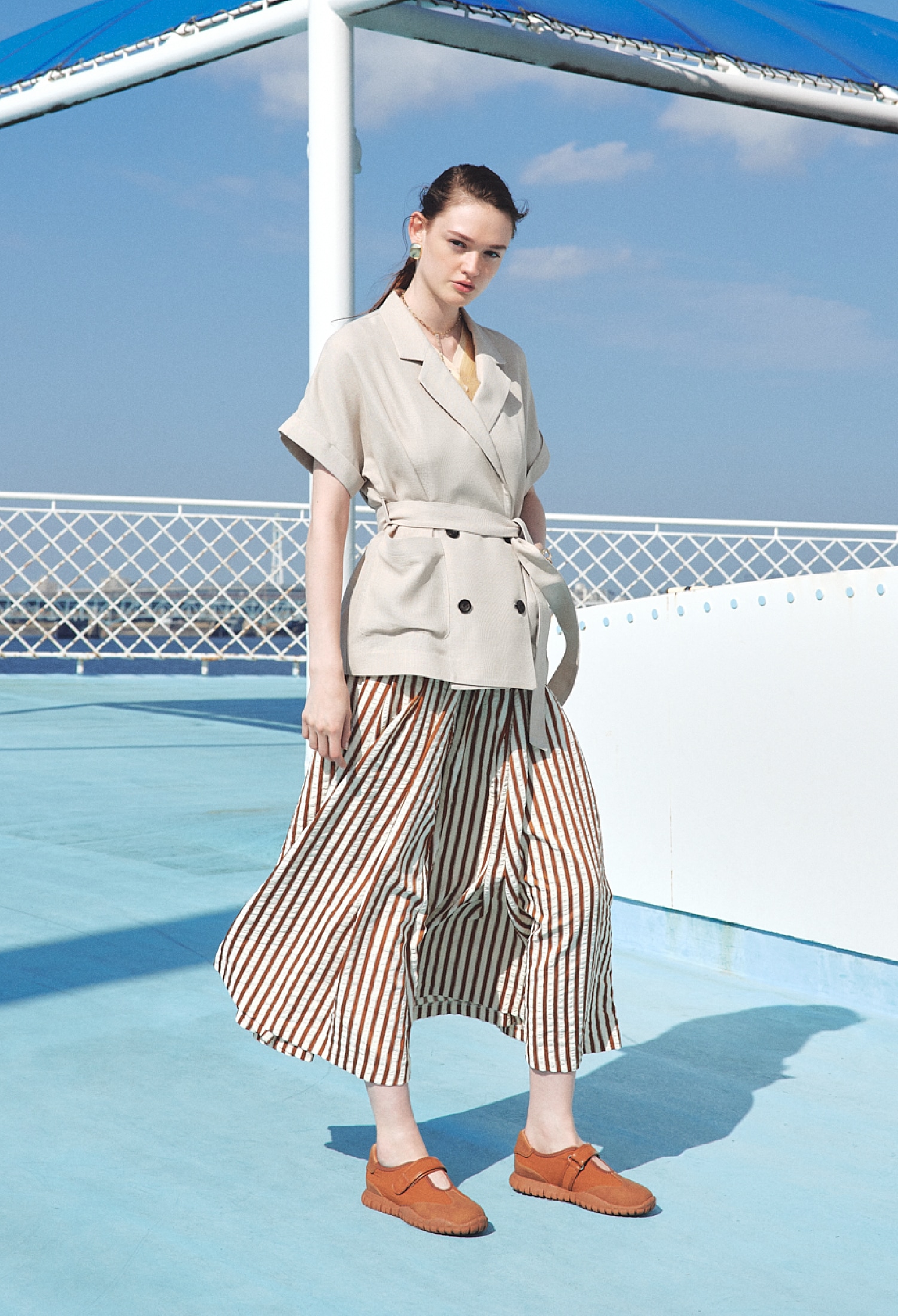 キャメルのサッカーストライプボリュームスカート・ゴールドのイヤリングとネックレスとバングル・キャメルのメリージェーンスニーカーを合わせたコーディネート