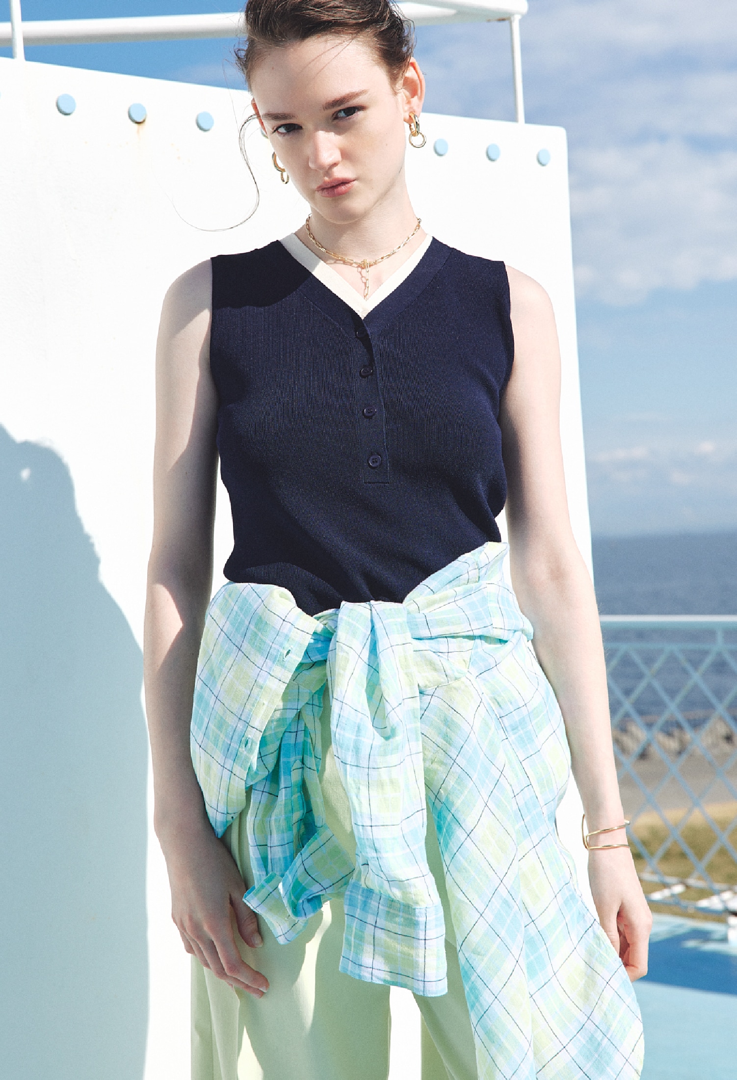 ネイビーのヘンリーネックニット・ライムのフレンチリネンシャツとセミワイドタックパンツ・ゴールドのイヤリングとネックレスとバングル・ミントのバッグとサングラスホルダーチャーム・オリーブのサンダルを合わせたコーディネート