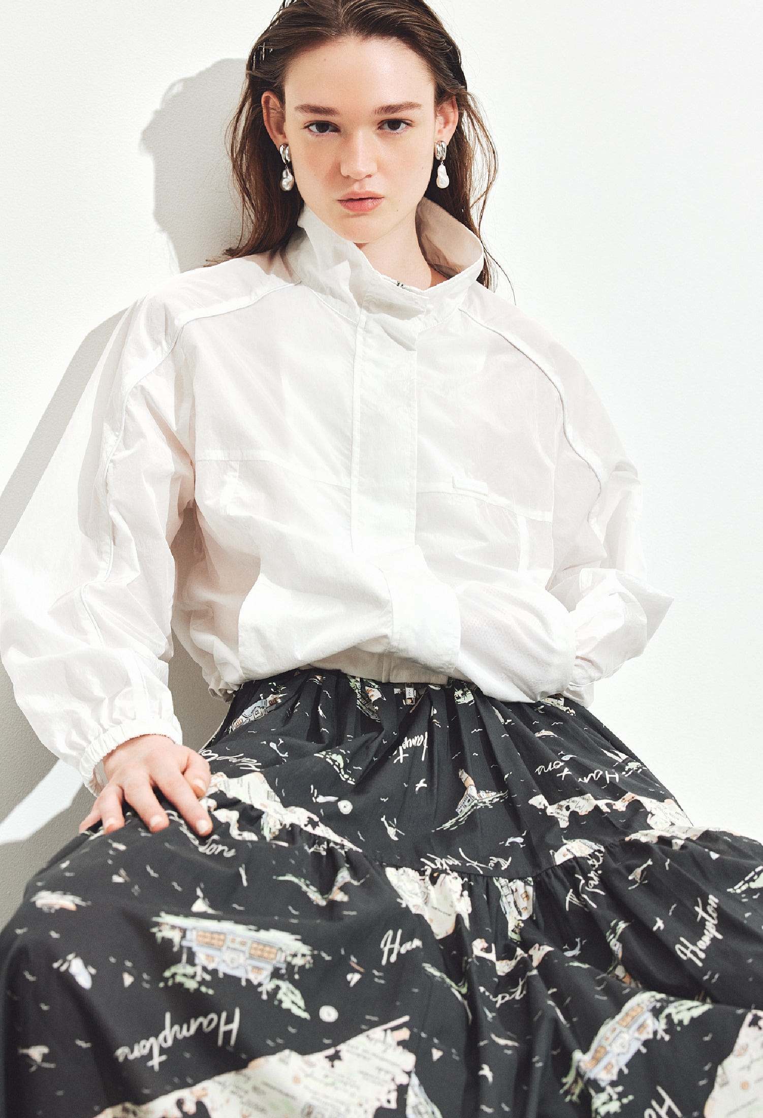 白のナイロントラックジャケット・チャコールグレーのティアードマキシスカート・シルバーのイヤリング・黒のメッシュローファーを合わせたコーディネート