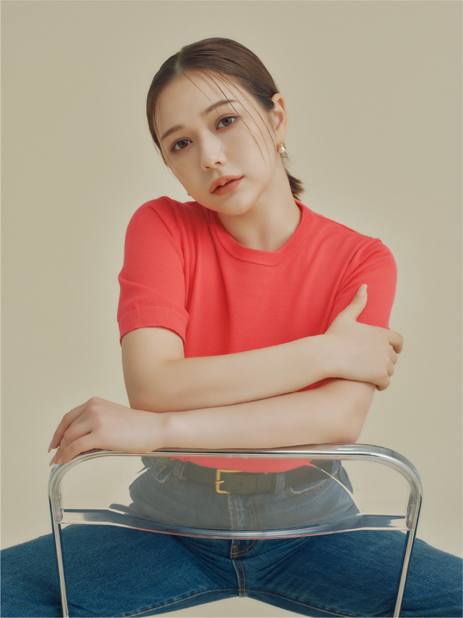 EC限定ニットアンサンブルとハイライズストレートデニムを着用し椅子に座ってるモデル画像