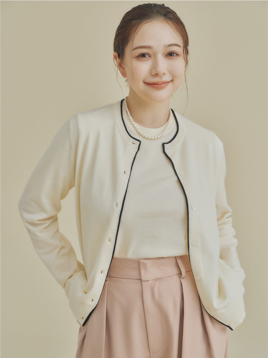 アイボリー色のEC限定ニットアンサンブル、ベージュ色のEC限定機能性パンツを着用した女性のイメージ
