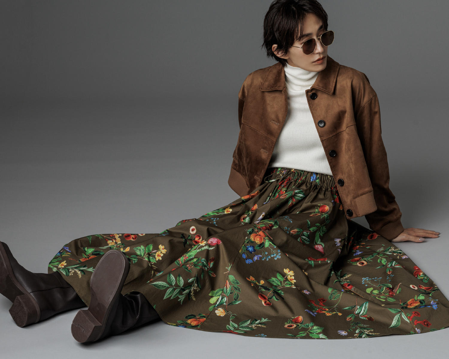 【セットアップ対応】スウェードブルゾン・タートルネックリブニットプルオーバー・ボタニカルウエストゴムギャザーマキシスカート・メタルスリムフレームサングラス・スクエアトゥロングブーツを着用した女性