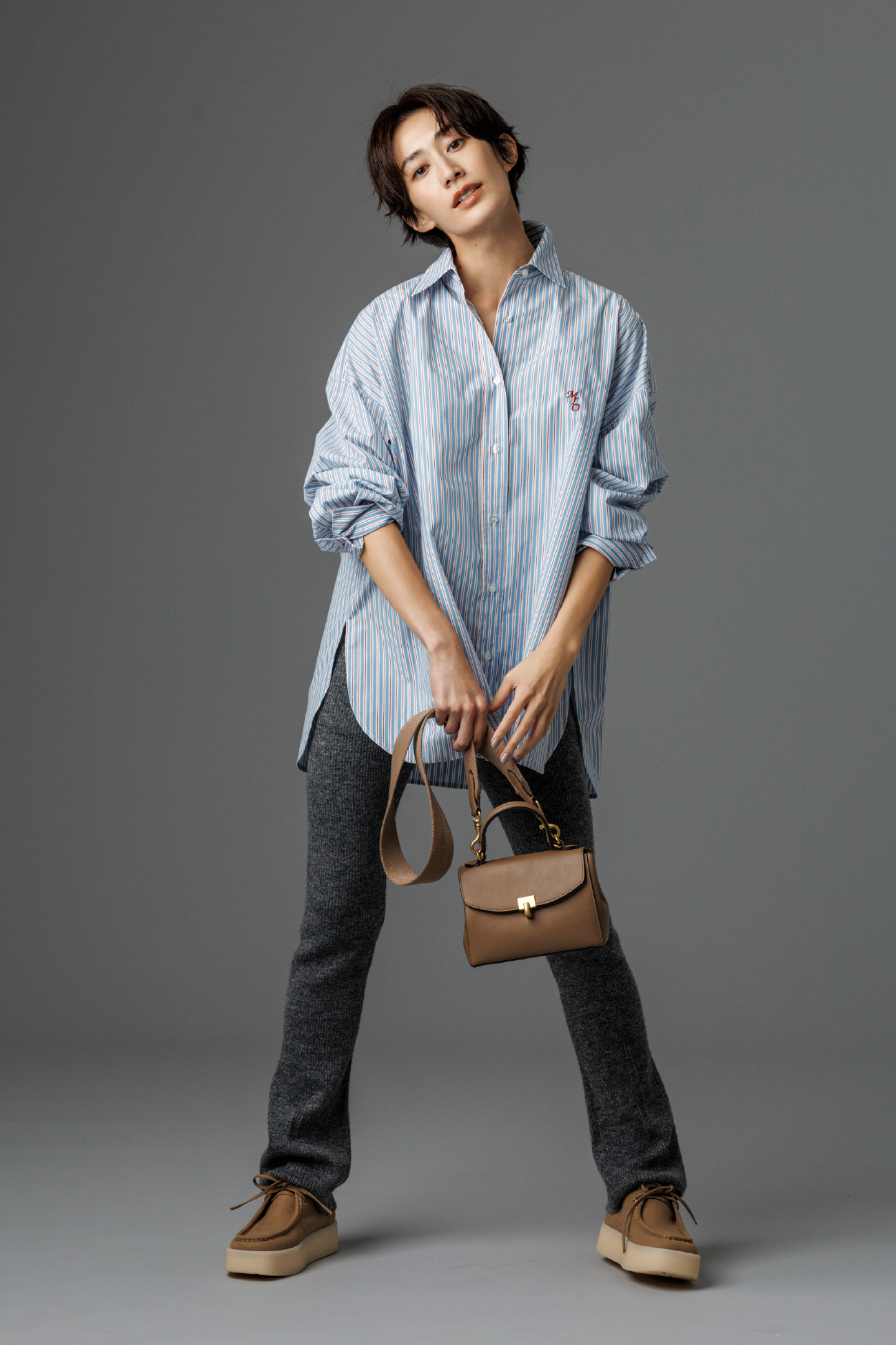 2WAYカシュクールーオーバーサイズシャツ・アルパカ混リブニットレギンスパンツ・メタルモチーフミニスクエアバッグ・レースアップシューズを着用した女性