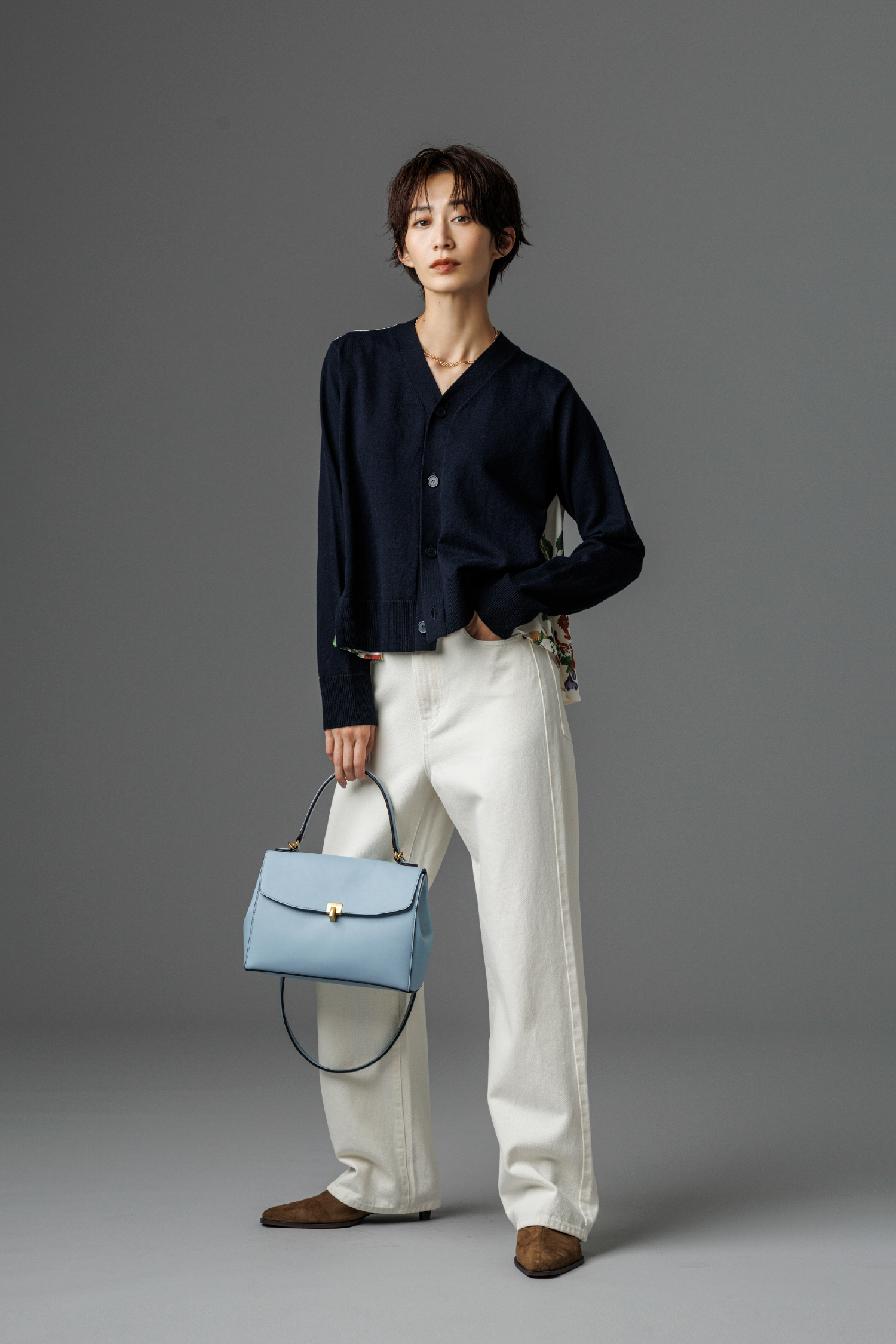 カシミヤコットンボタニカルドッキングカーディガン・細ベルト付きストレートデニムパンツ・ロングチェーンネックレス・メタルモチーフスクエアバッグ・キトゥンヒールショートブーツを着用した女性