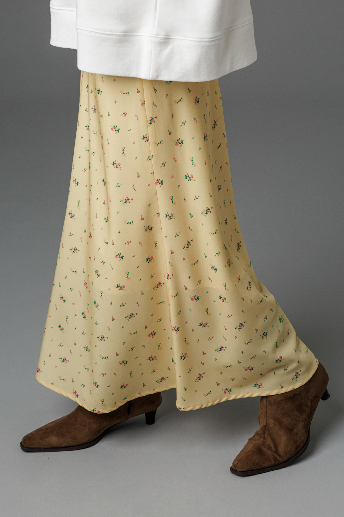 フォルムスリーブ裏起毛フーディー・小花柄プリントナロースカート・キトゥンヒールショートブーツを着用した女性の足元