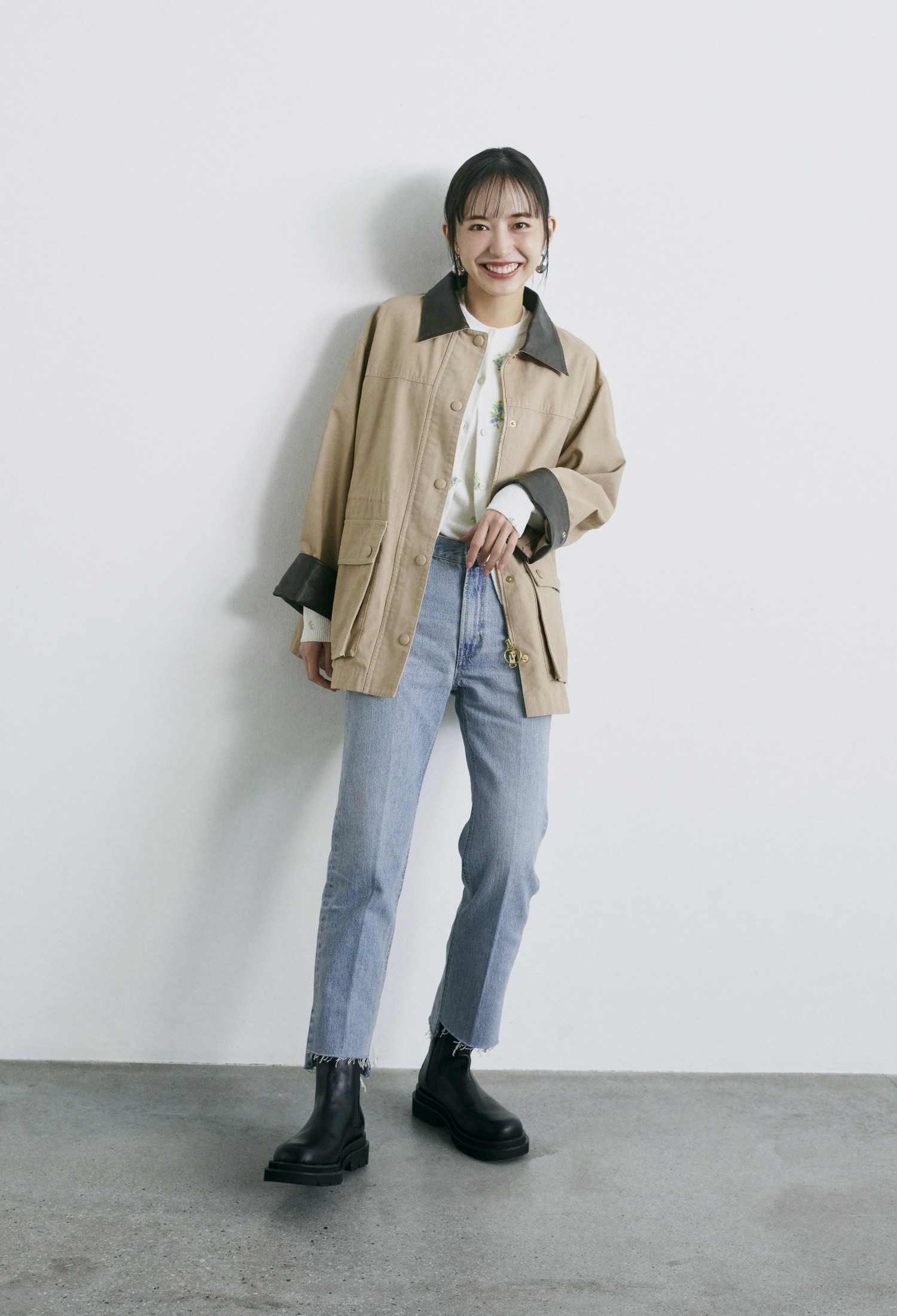 ベージュのハーフ丈ハンティングジャケット・ブルーのフラワープリントアンサンブルカーディガン・ライトブルーの裾段差テーパードデニムパンツ・シルバーのメタルドロップピアス・黒のサイドゴアブーツを合わせたコーディネート