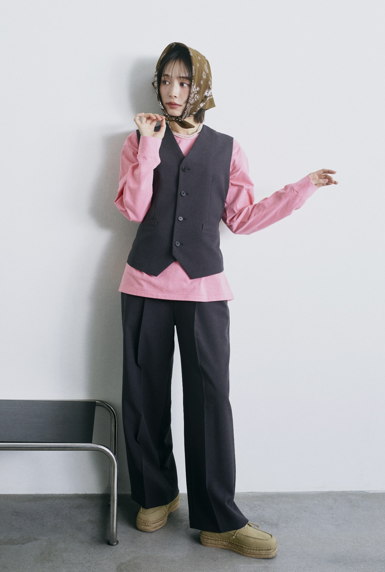 チャコールグレーの後ろバックル付きベスト・ピンクの３段ロゴグラフィックロンＴシャツ・チャコールグレーのセンタープレスイージーパンツ・ブラウンのバンダナ柄綿シルクスカーフ・白のメタルリングパールロングネックレス・キャメルのエスパドリーユシューズを合わせたコーディネート