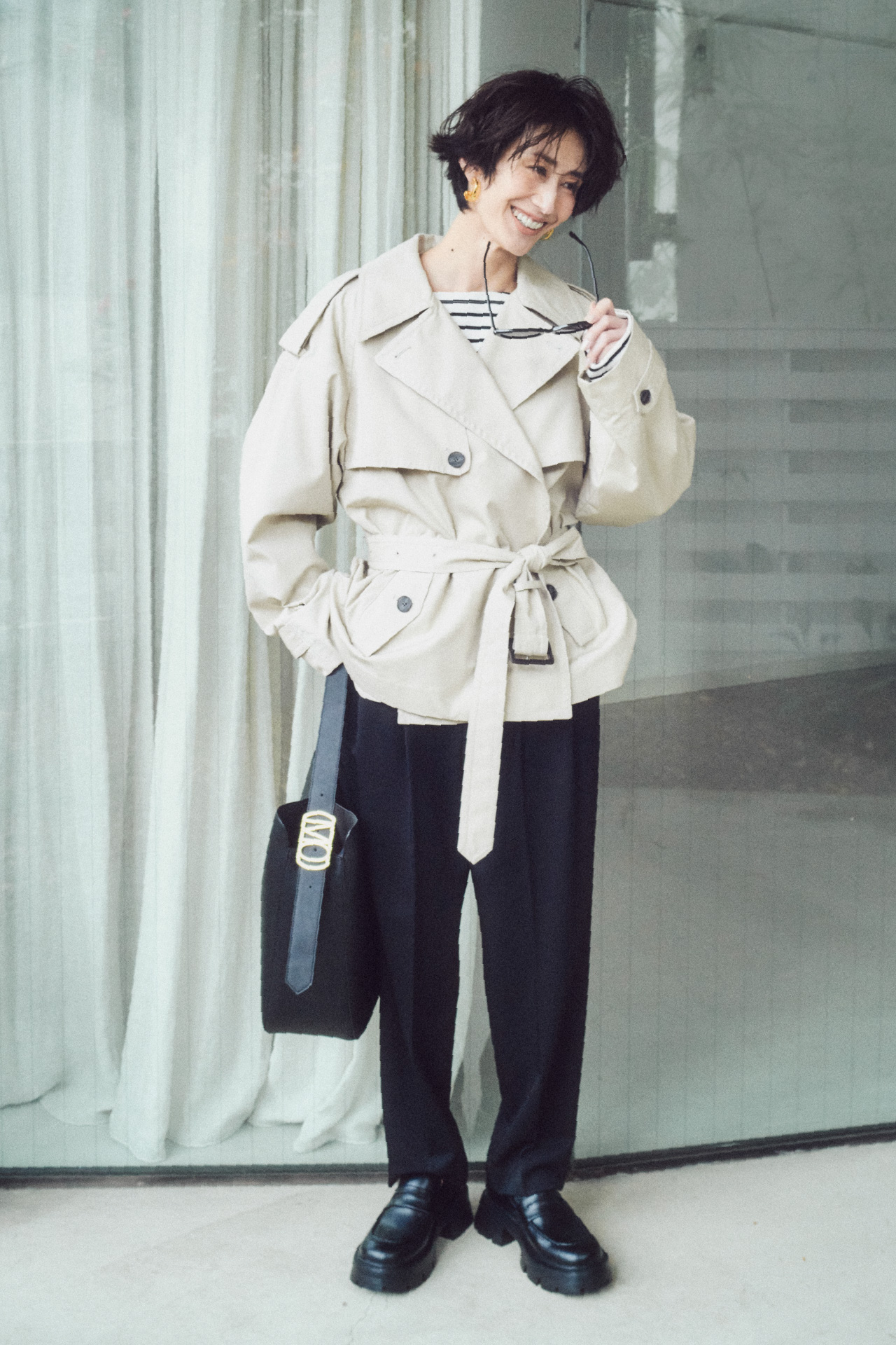 ショートトレンチコート、ボートネックボーダーＴシャツ、２タックテーパードＰＴ、メタルドロップフープイヤリング、バックルモチーフバケットバッグ、モカシンローファーを着用したモデル画像