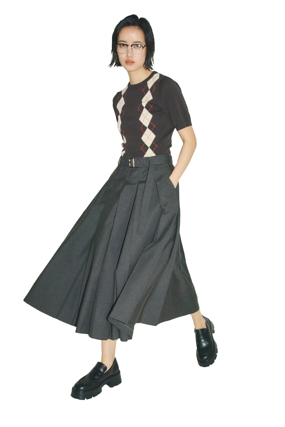 ミックスカラーのシェル釦デザインクロップドニットカーディガンとプリーツスカートニットドッキングワンピース・黒のハーフリムフレームダテメガネとモカシンローファーを合わせたコーディネート