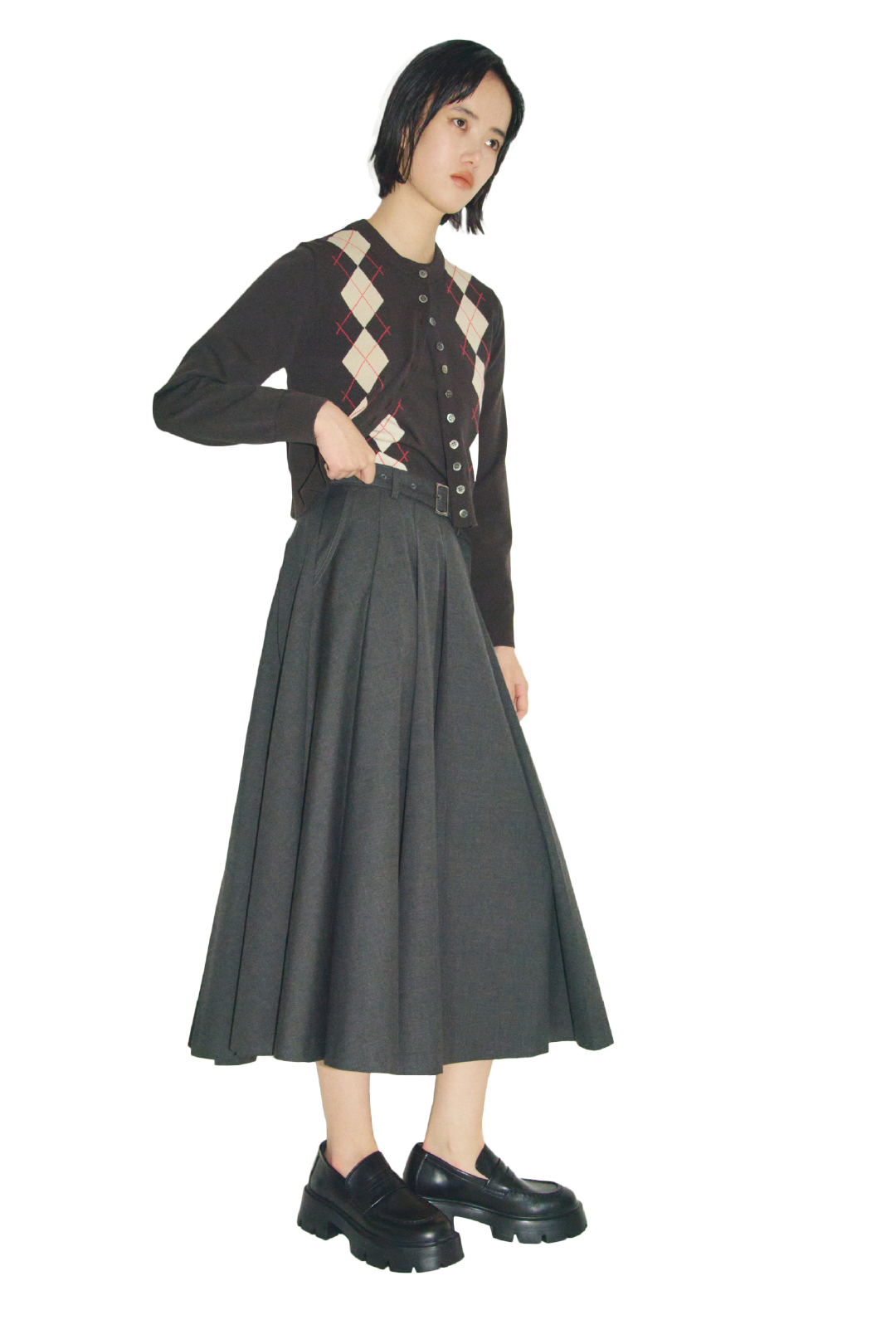 ミックスカラーのシェル釦デザインクロップドニットカーディガンとプリーツスカートニットドッキングワンピース・黒のハーフリムフレームダテメガネとモカシンローファーを合わせたコーディネート