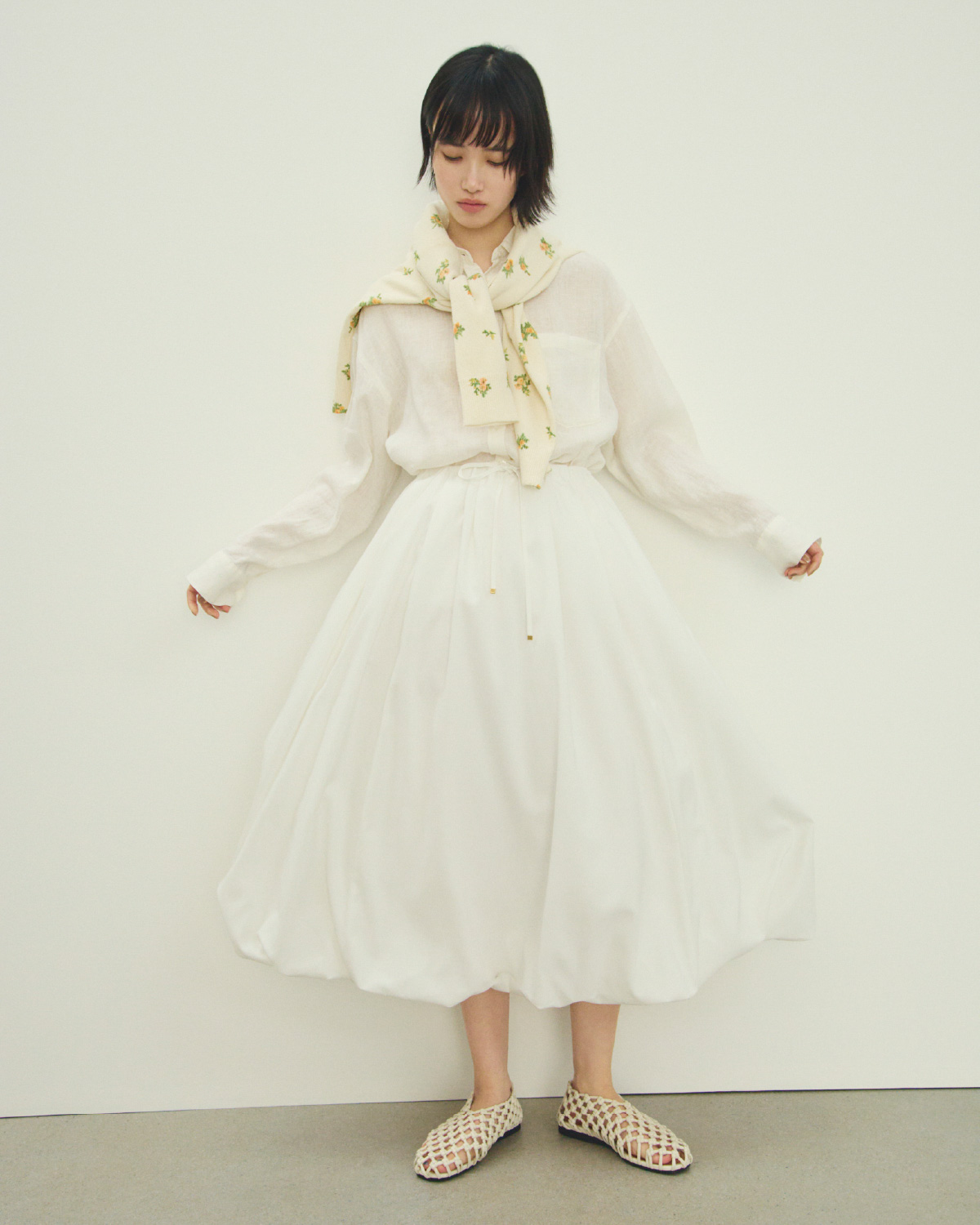 白色のポケット付きフレンチリネンＳＨ、フラワープリントアンサンブルＣＤ、アイボリー色のリネン混バルーンシャツＯＰとメッシュバレエを合わせたコーディネート