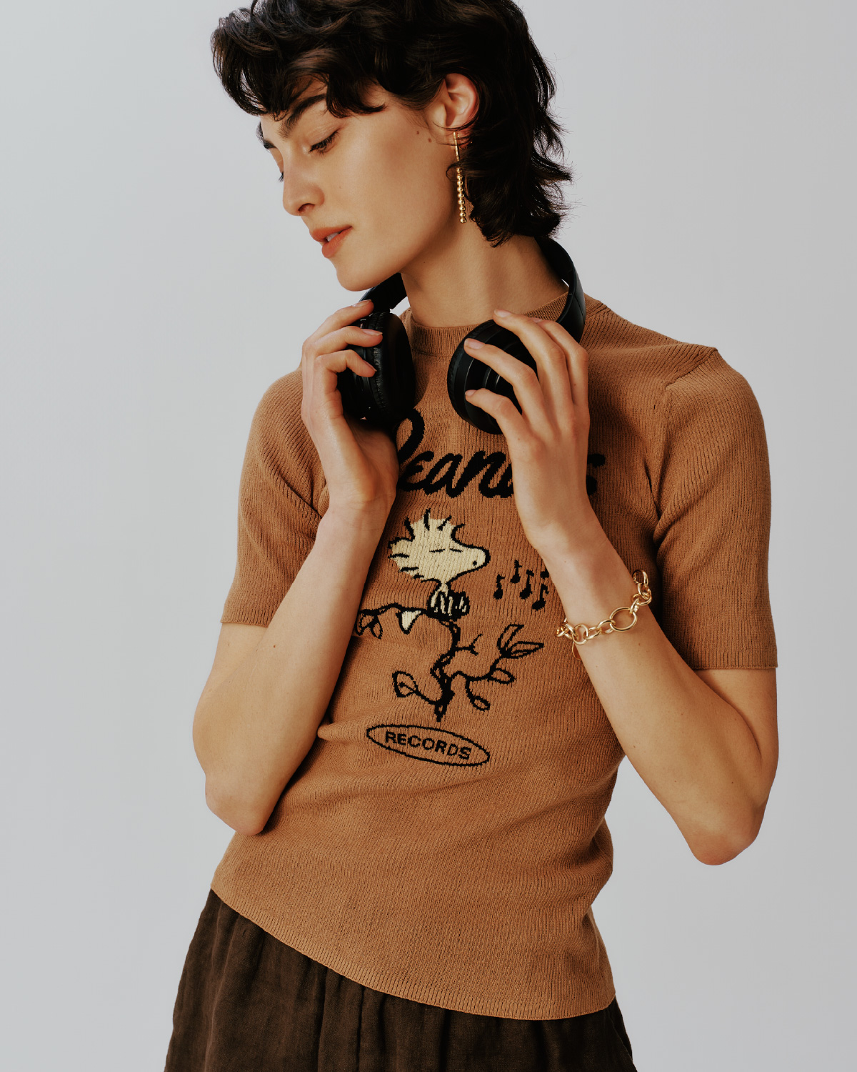 ベージュ色のＰＥＡＮＵＴ【ＷＳ】ジャガードリブニット、フレンチリネンショートＰＮ、メタルボールチャームイヤリング、コインモチーフチェーンブレスを着用した女性の画像