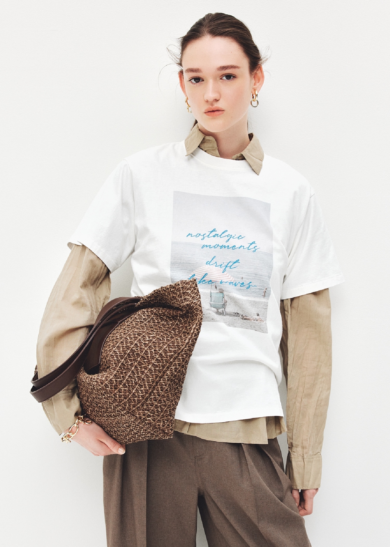 白のフォトプリントTシャツとベージュのオーバーシャツとモカの２タックワイドパンツとイヤリングブレスレットとラージトートバッグを合わせたコーディネート